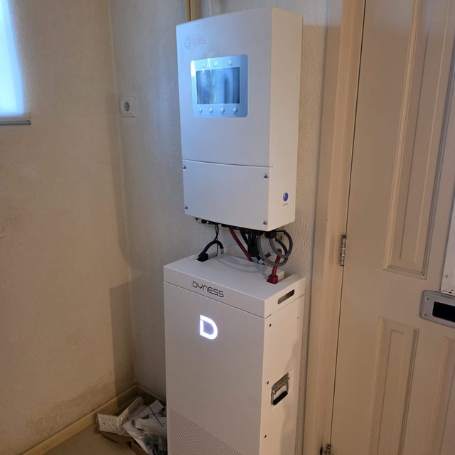 Omvormer boven een thuisbatterij in een bijruimte